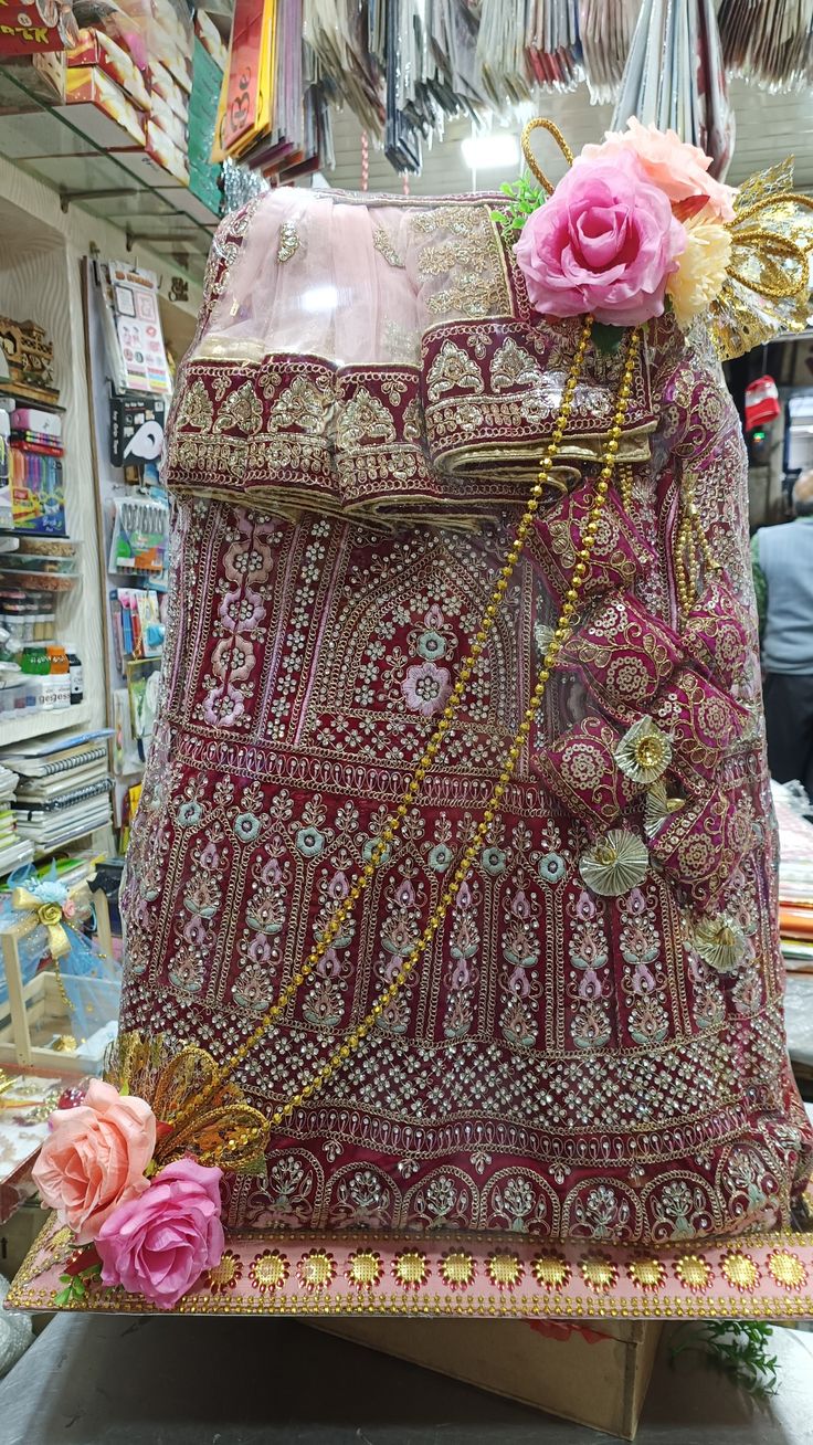 a pink and gold purse sitting on top of a wooden stand in a store next to flowers