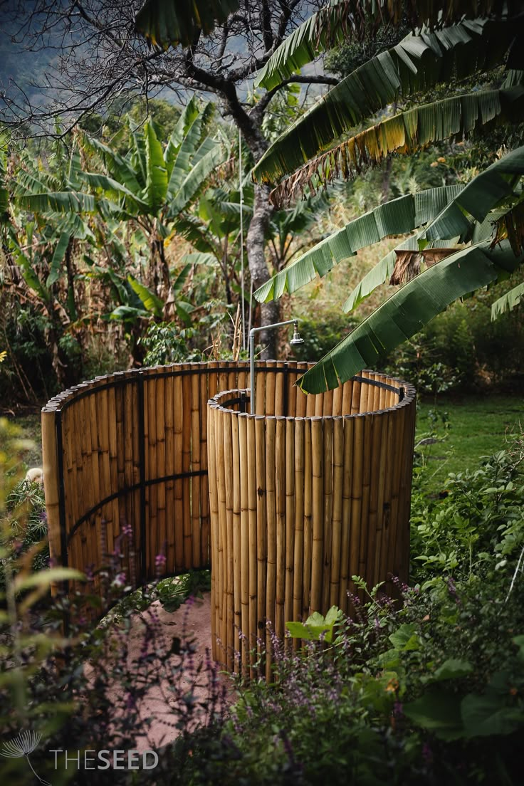 a bamboo planter in the middle of a garden with trees and plants around it