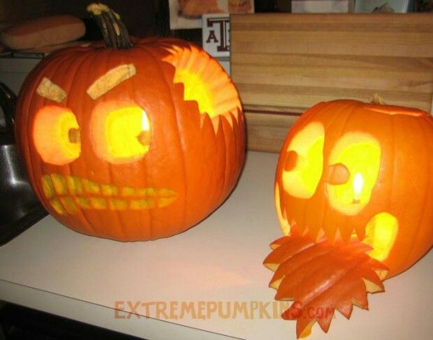 two pumpkins with faces carved into them sitting on top of a counter next to each other