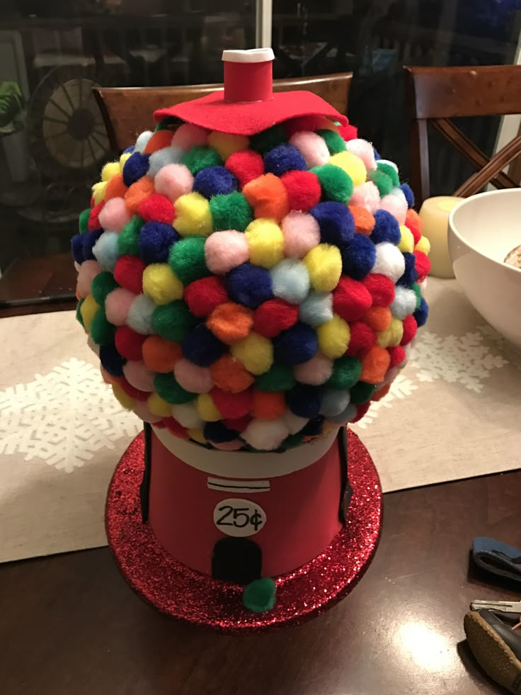 a gummy machine covered in multicolored pom - poms sits on a table