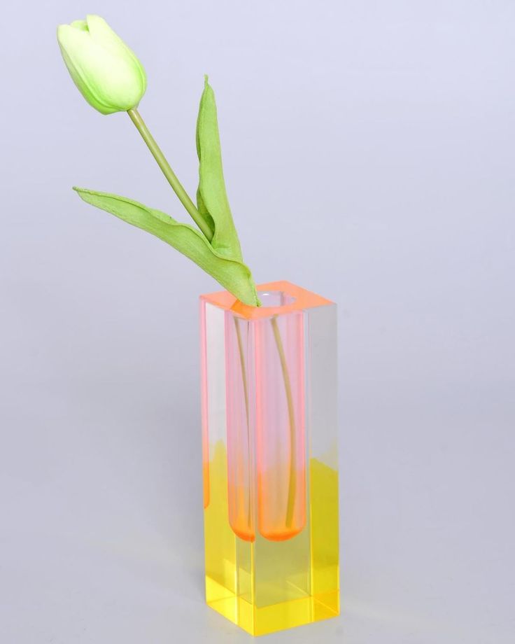 a yellow and pink vase with a single flower in it