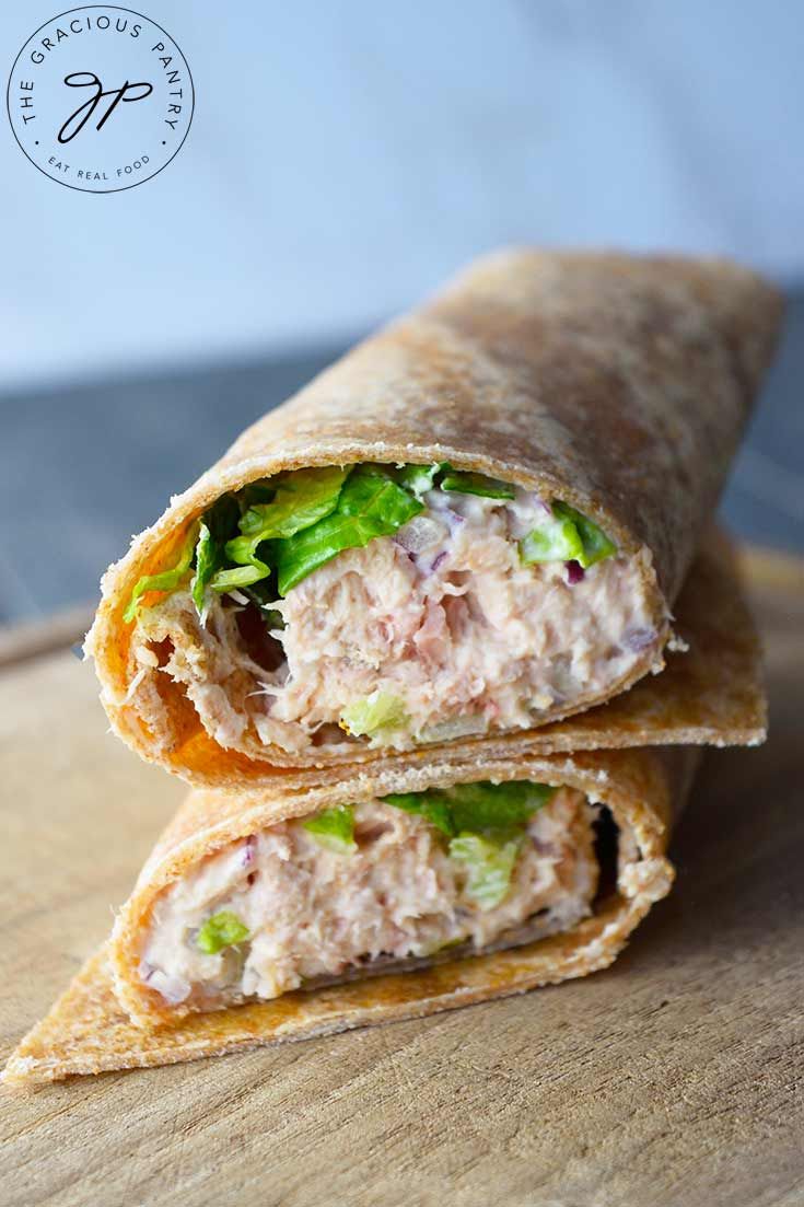 a wrap filled with meat and lettuce on top of a wooden cutting board