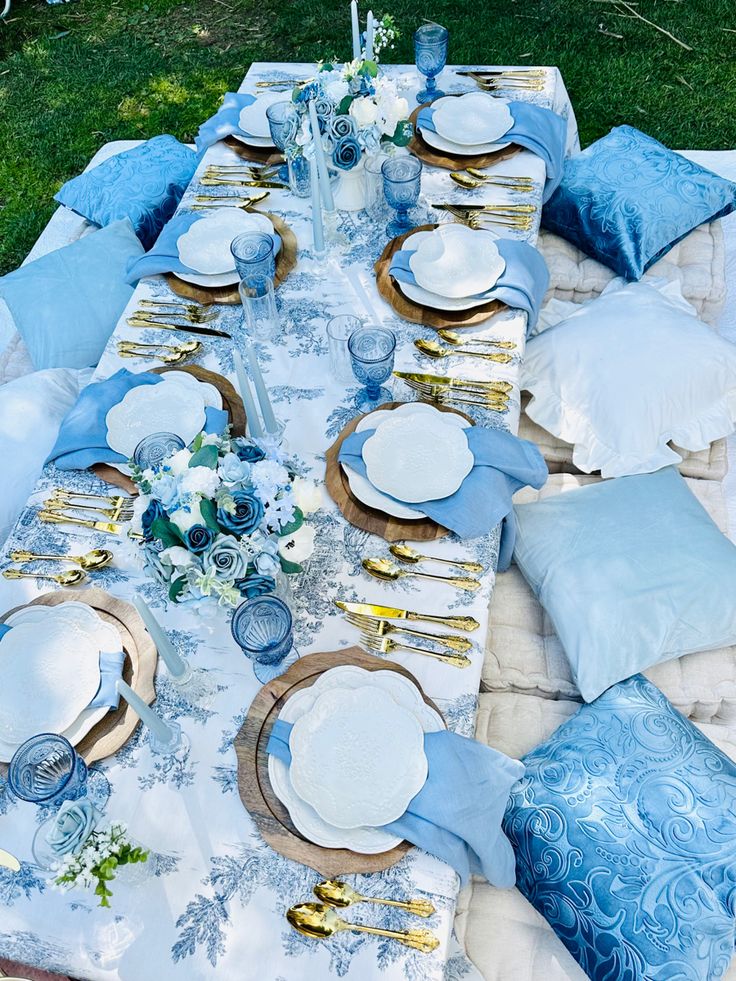 a table set up with blue and white plates, napkins and place settings on it