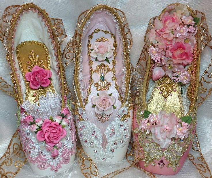 three pink and gold shoes with flowers on the bottom, one is decorated like a shoe