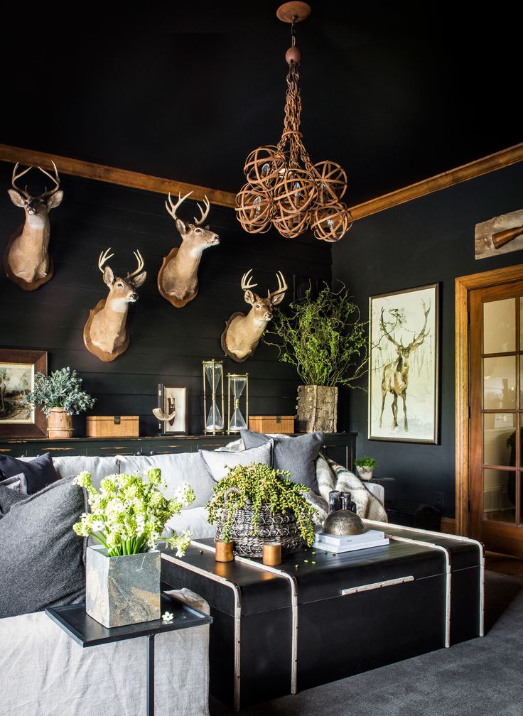 a living room with deer heads on the wall and plants in vases hanging from the ceiling