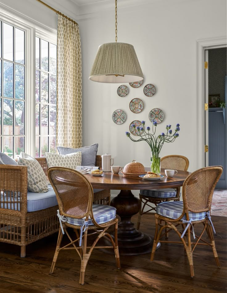 a dining room with wicker chairs and wooden table