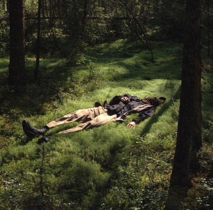 two people laying on the ground in the woods