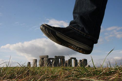 a person standing on top of a grass covered field next to an object in the air