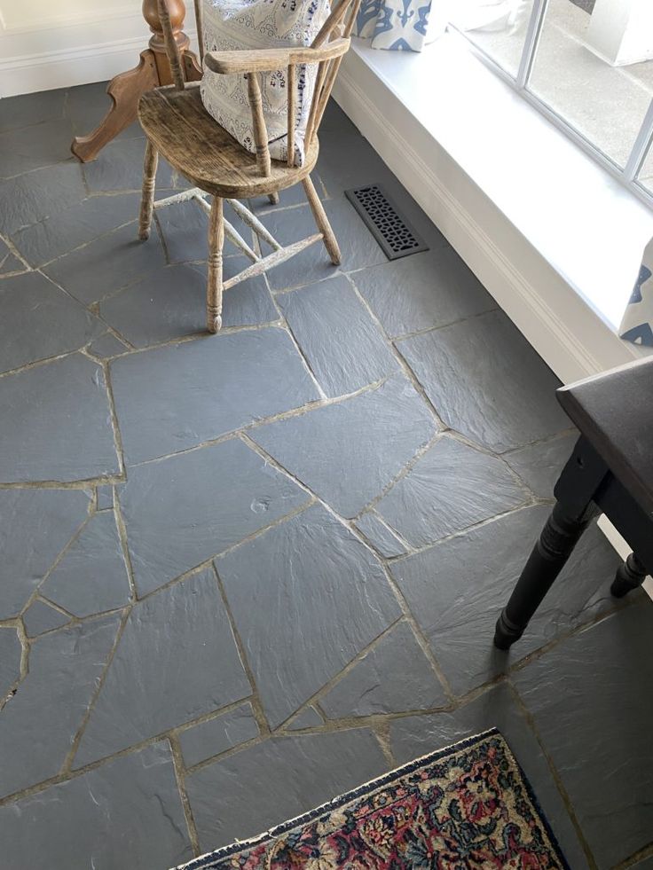 a chair sitting on top of a stone floor next to a window