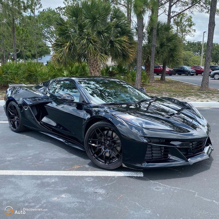 a black sports car parked in a parking lot with palm trees and other cars behind it