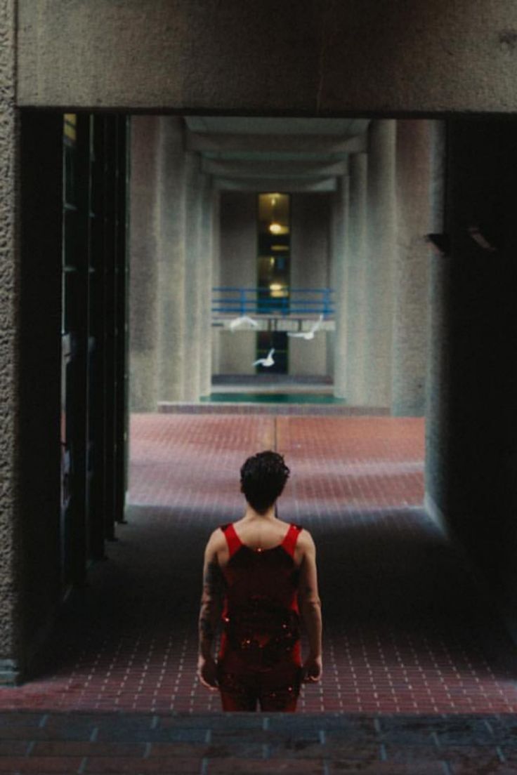 a woman in red dress walking through an open doorway to another building with columns on either side