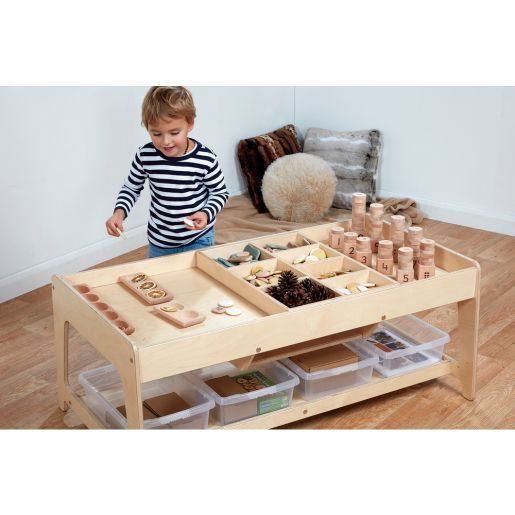 a young boy playing with wooden toys on the floor in front of a coffee table