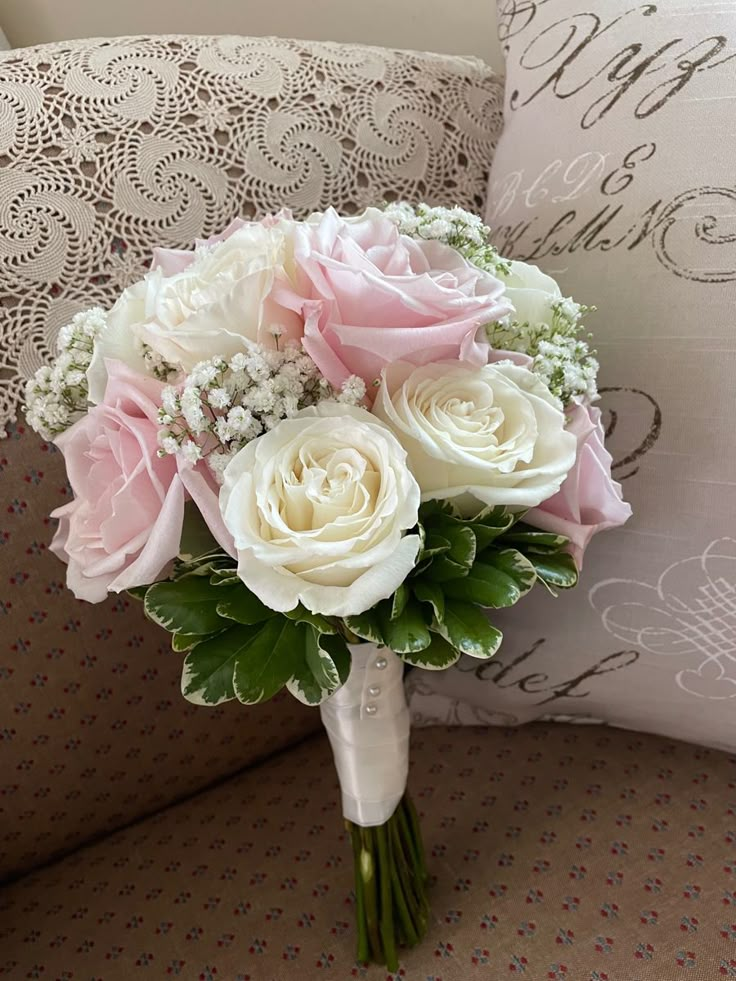 a bridal bouquet sitting on top of a couch in front of a decorative pillow