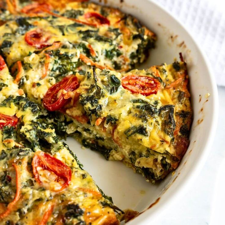 an omelet with tomatoes and spinach in a white dish