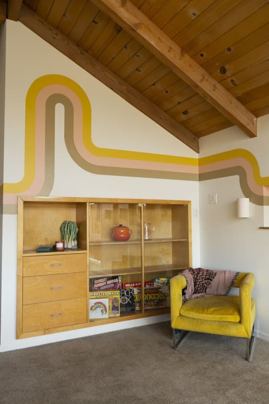 a yellow chair sitting in front of a book shelf on top of a carpeted floor