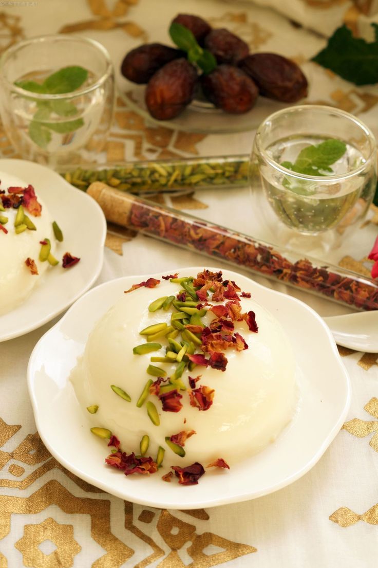 two white plates topped with desserts on top of a table next to glasses and utensils