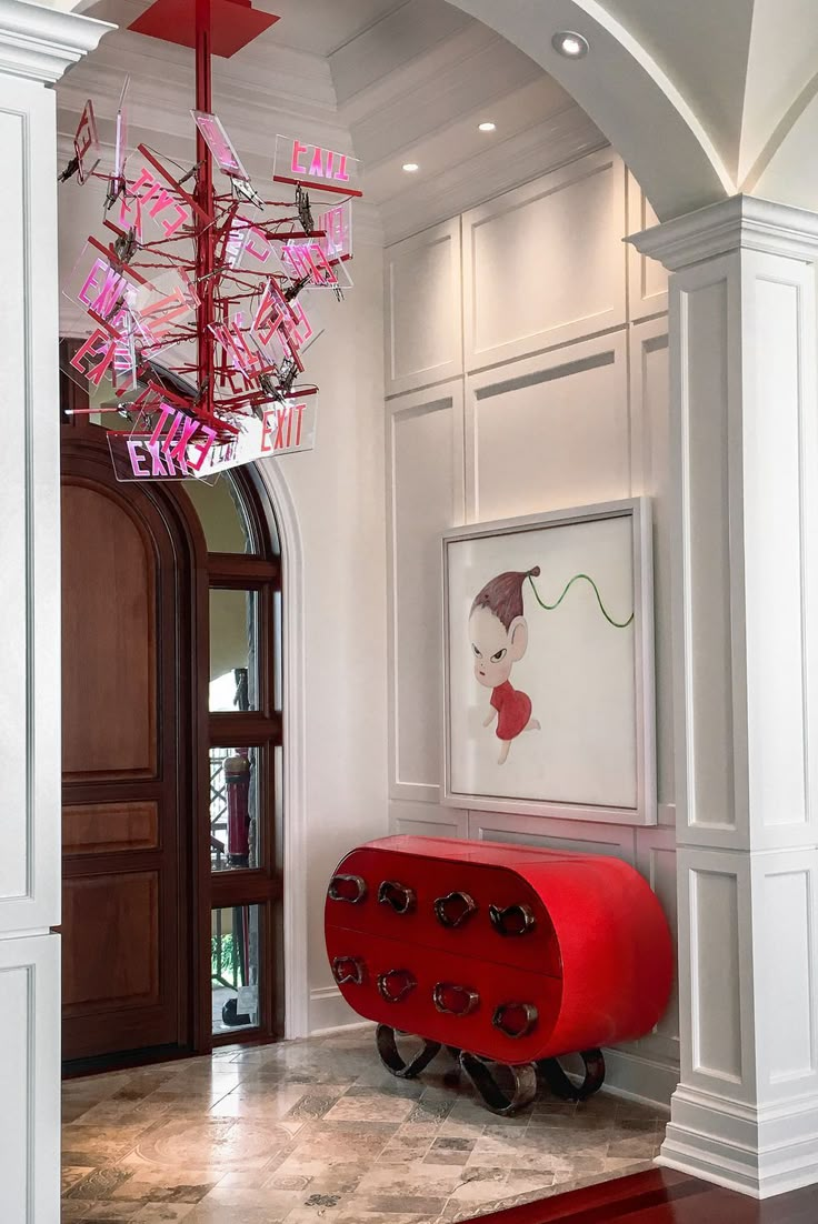 a red cart sitting in the middle of a hallway next to a doorway with a chandelier above it