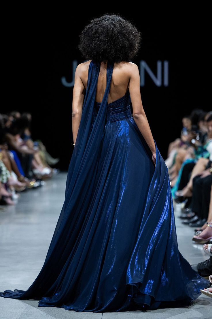 a woman in a blue dress walking down the runway