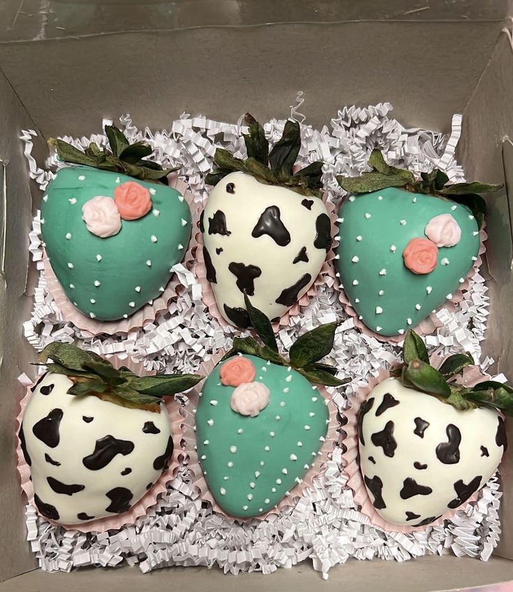 four decorated strawberries are in a box