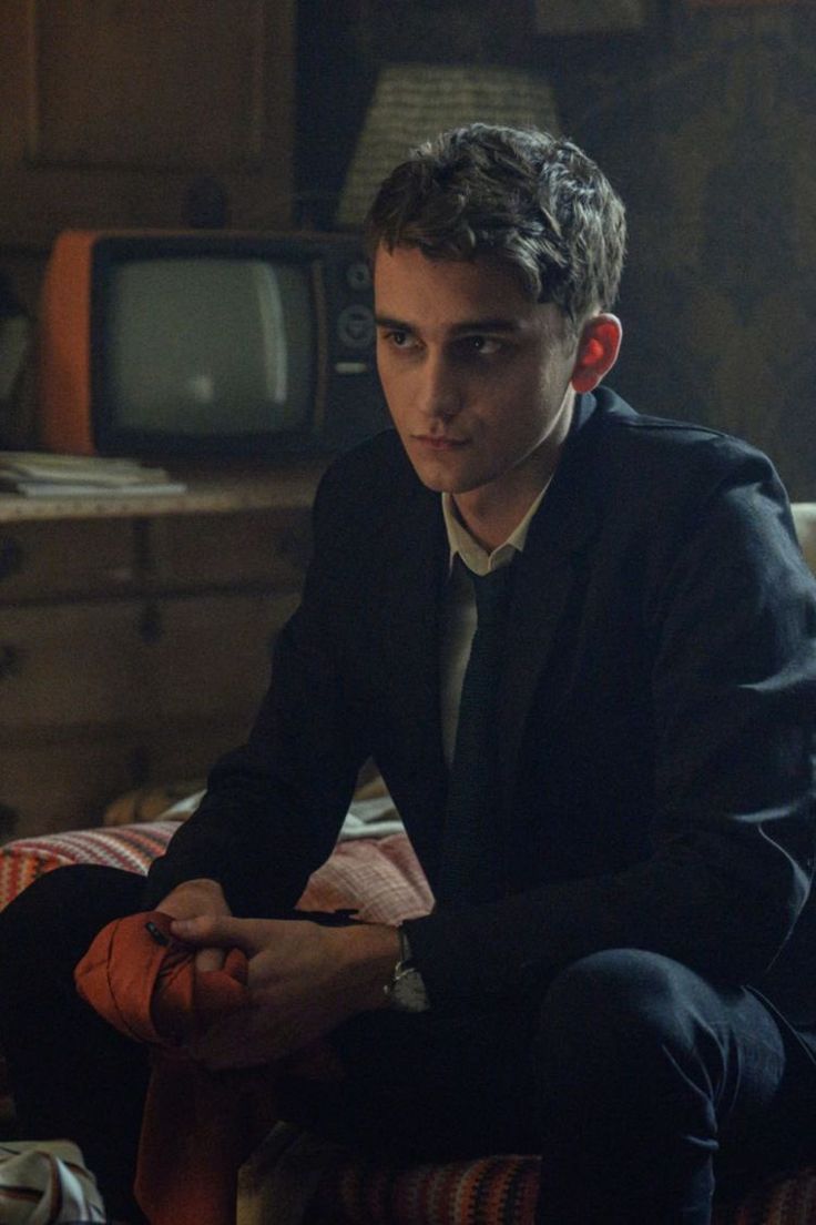 a man sitting on top of a couch in front of a tv set and looking at the camera