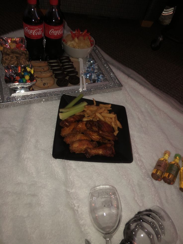 a table topped with plates and glasses filled with food next to bottles of sodas