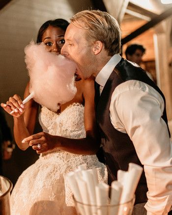 a bride and groom are kissing while holding cotton floss in front of their face