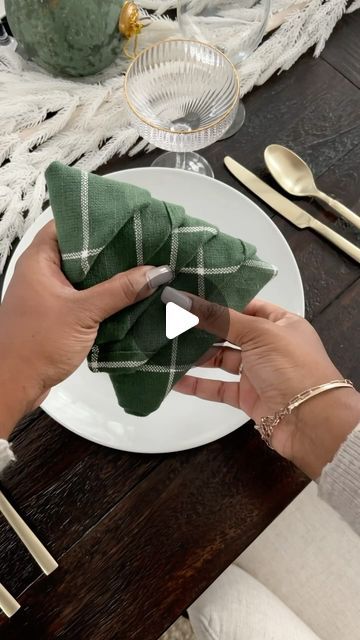 a person holding a napkin over a white plate with silverware on top of it