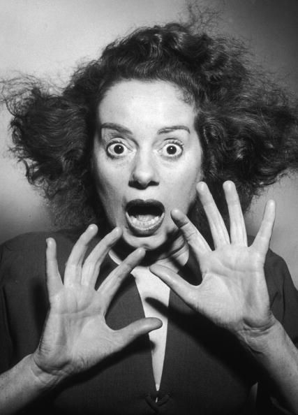 a woman with her hands in front of her face making the shape of two hands