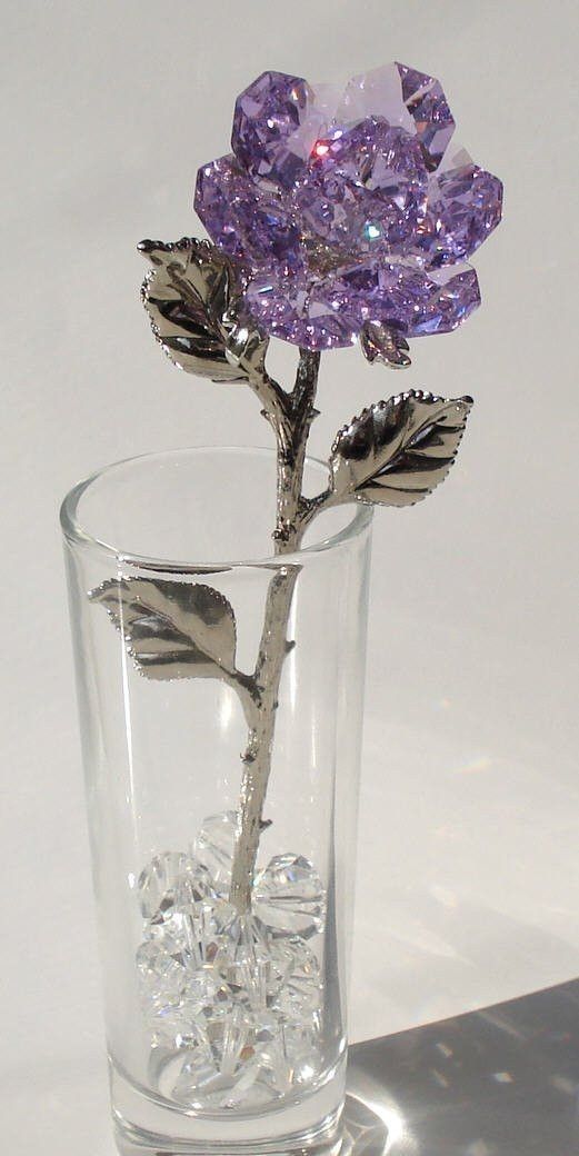 a purple flower in a glass filled with ice cubes on a white table top