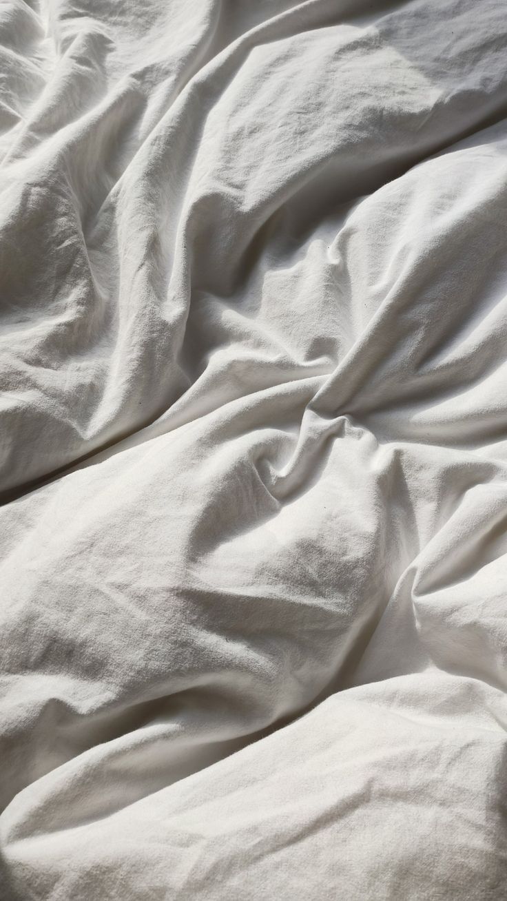 an unmade bed with white sheets and pillows