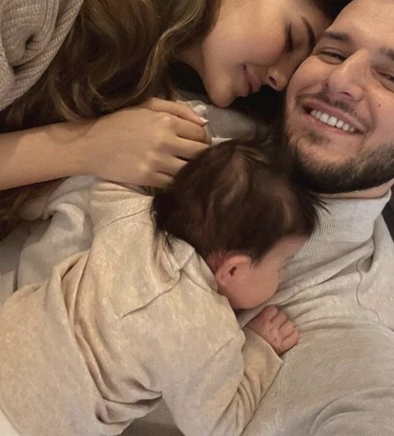 a man and woman laying on top of a bed with a baby in their arms