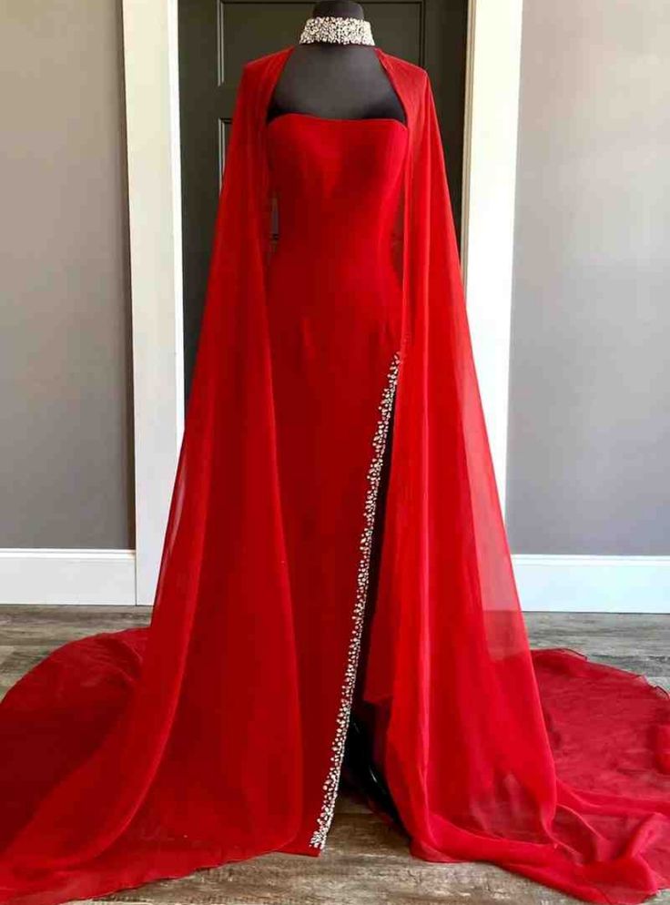 Function meets elegance in this red prom gown, where style is rivaled only by sophistication. A single cape-like sleeve emerges from a bodice adorned with intricate rhinestone details, creating a silhouette that is both modern and timeless. The sleek design carves a figure-enhancing line that flows into a luxuriously long train, guaranteeing a stunning silhouette from every angle. This dress is not just a fashion statement, but a wearable work of art, ensuring any prom night becomes a spectacular event. Red Fantasy Wedding Dress, Red Dress With Cape, Red Fantasy Gown, Red Fantasy Dress, Prom Dress With Cape, Red Cape Dress, High Neck Long Sleeve Wedding Dress, Red Long Prom Dress, Red And Blue Dress