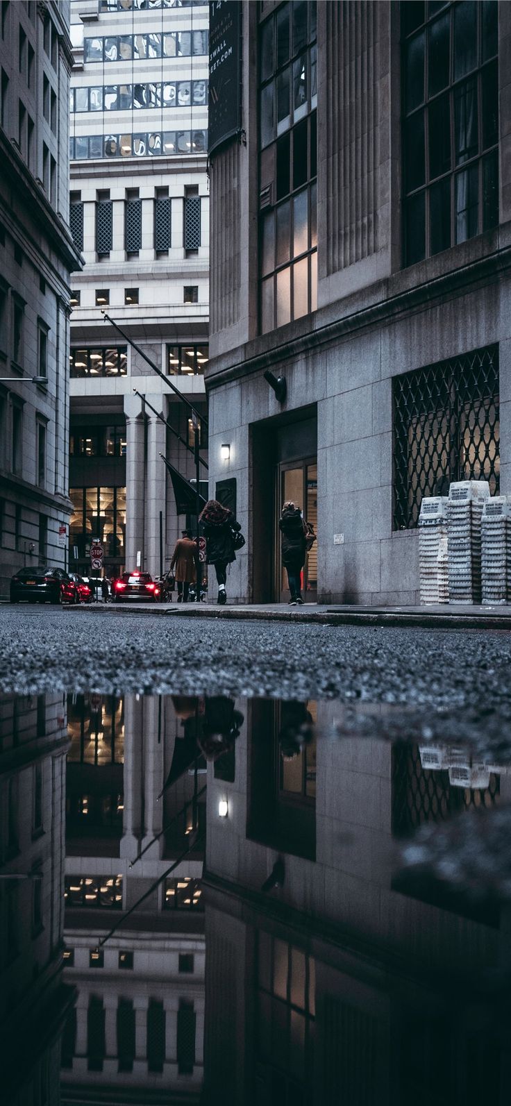 an empty city street at night with buildings reflected in the puddles on the pavement