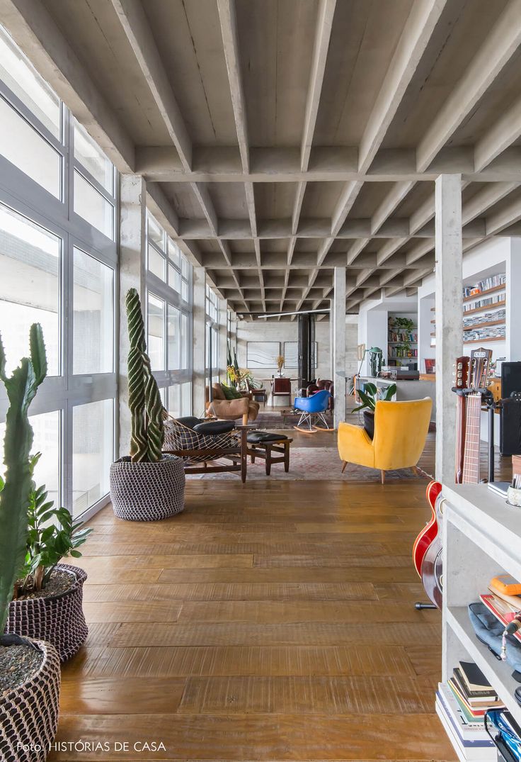 an empty room with wooden flooring and large glass windows on the wall, filled with potted cacti