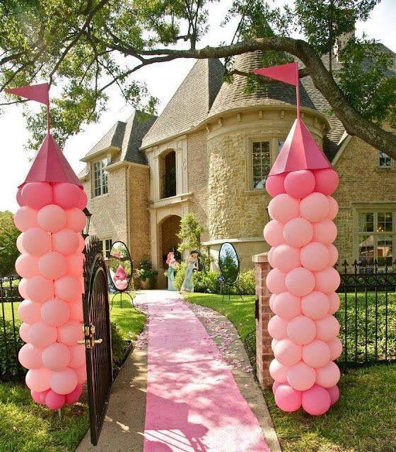 pink balloons are placed in front of an entrance to a large house with a gate