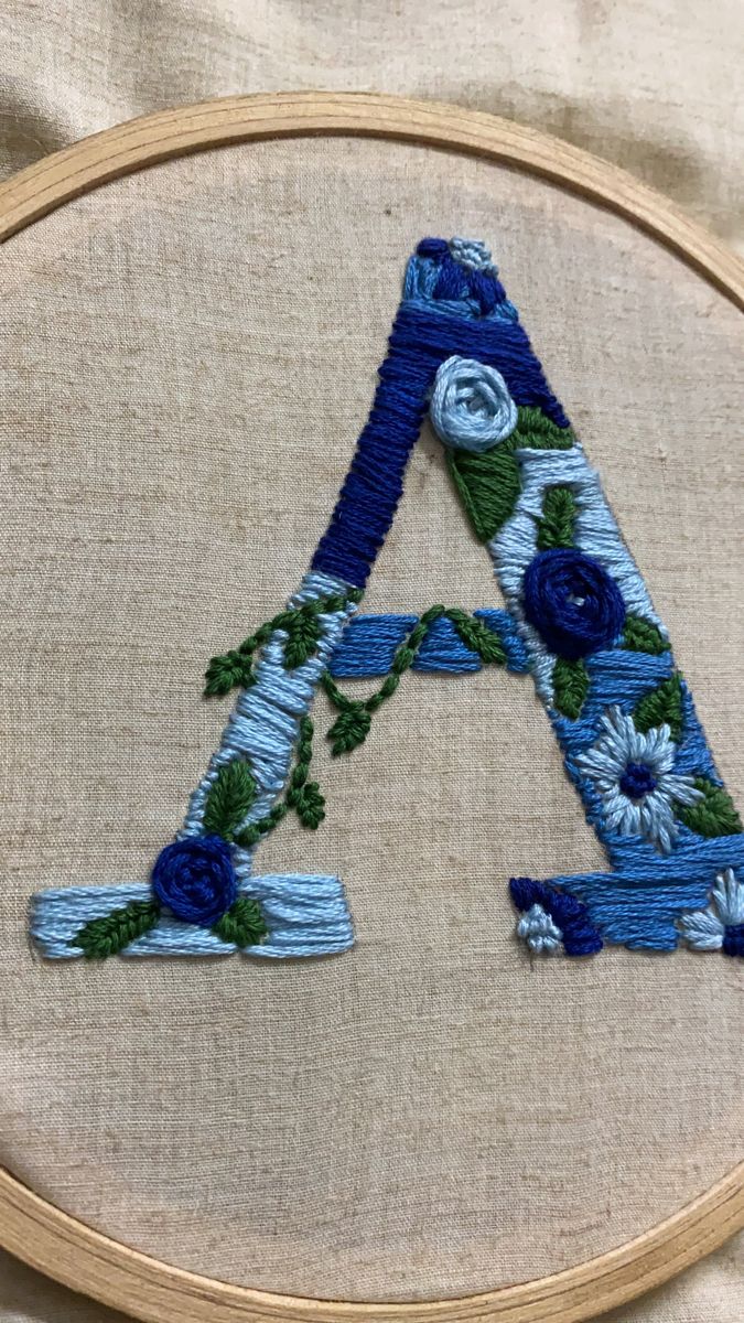 an embroidered letter with blue flowers on it