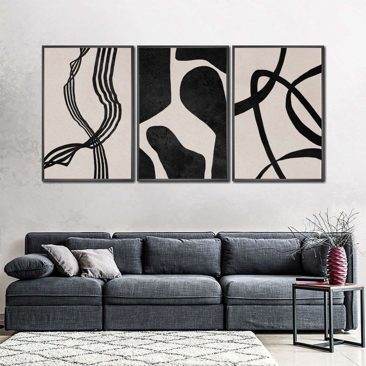 a living room with two black and white paintings hanging on the wall next to a gray couch