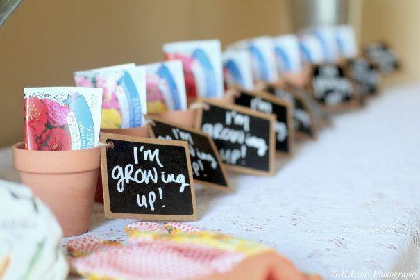 a table topped with cards and potted plants next to a chalkboard sign that says i'm growing up