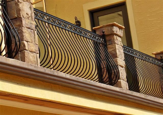 a balcony with wrought iron railings and decorative stone pillars on the side of a building