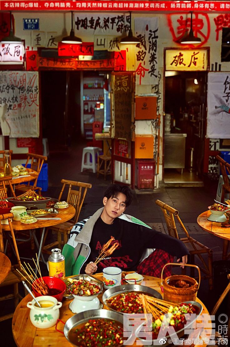 a man sitting at a table with food on it in front of some chinese signs