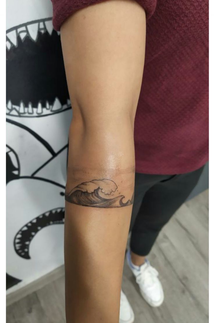 a woman's arm with a tattoo on it and a wave in the middle