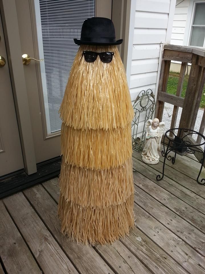 a man in a straw hat and sunglasses standing on a porch with a fake grass skirt