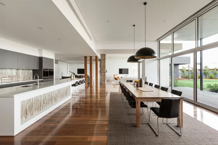 a large dining room table and chairs in front of an open kitchen with sliding glass doors