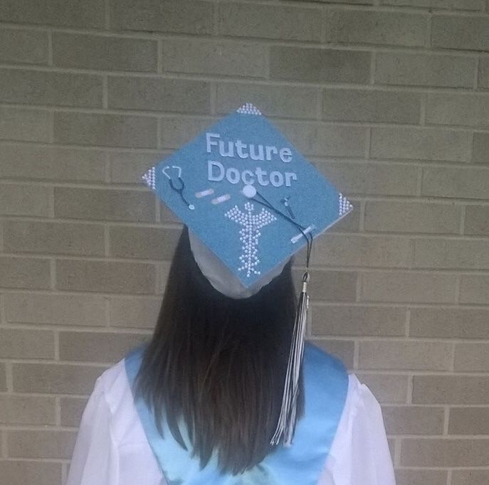 a woman wearing a blue graduation cap with the words future doctor on it's side