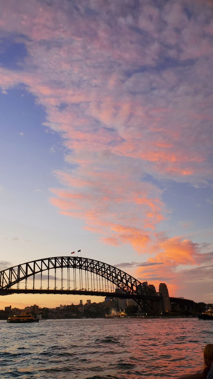 the sydney harbour bridge at sunset with pink clouds