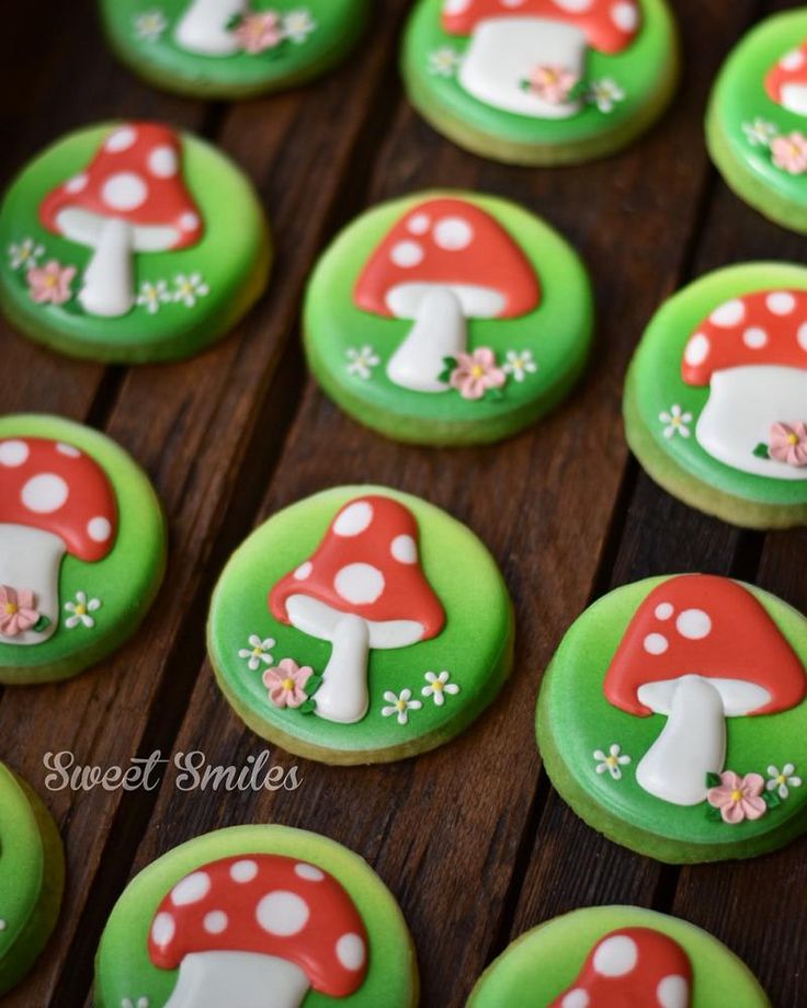 decorated cookies with green frosting and white mushrooms on them, sitting on a wooden table