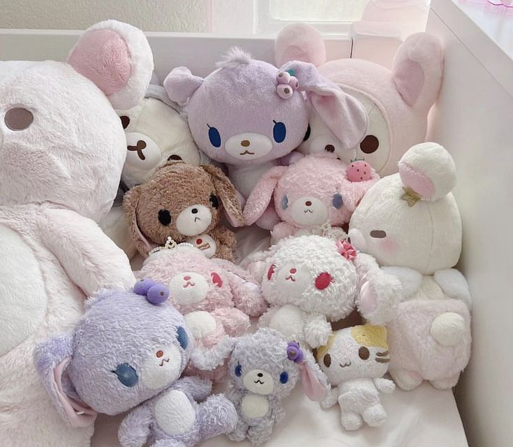 a pile of stuffed animals sitting on top of a white bed next to a window