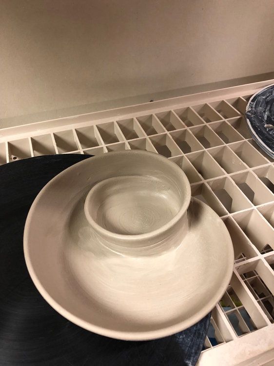 two white bowls sitting on top of a black plate in front of an empty dish drainer