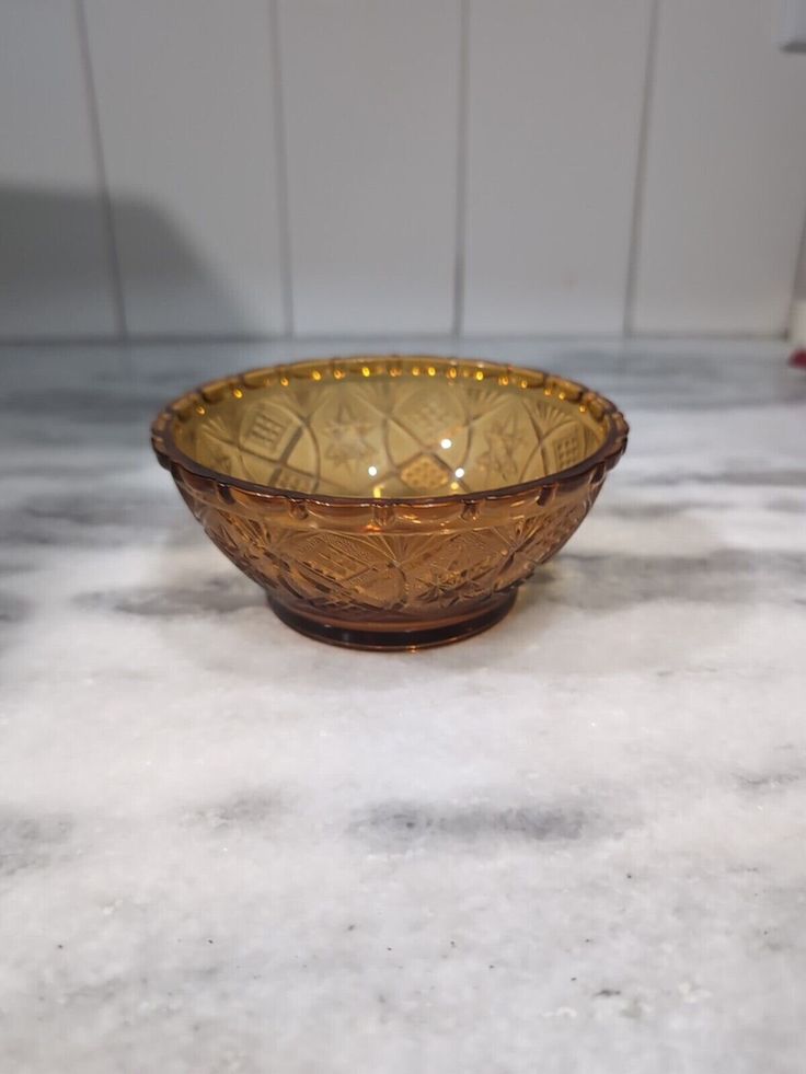 a brown glass bowl sitting on top of a white marble countertop next to a wall