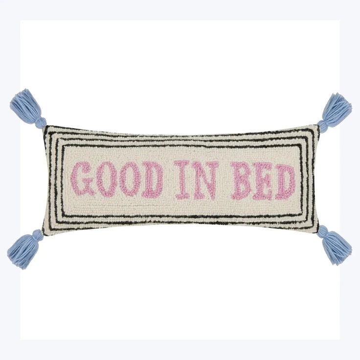 a pillow that says good in bed with tassels on the front and back